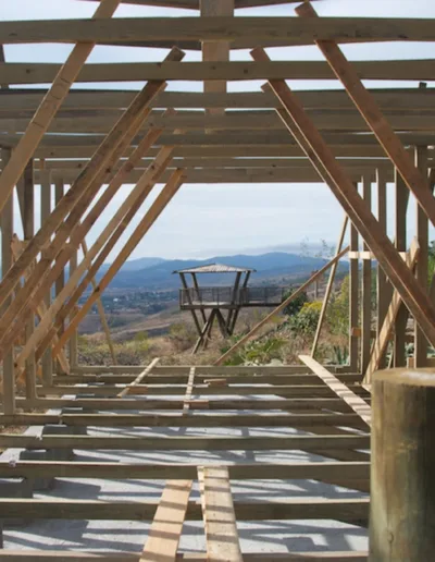 The inside of a wooden structure with a view of the mountains.