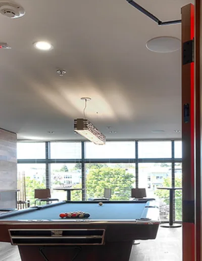 A room with a pool table and a red neon sign.