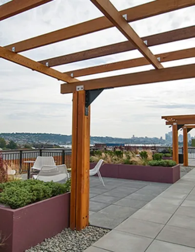 A wooden pergola on a rooftop with a view of the city.
