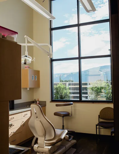 A dentist's office with a chair and a window.