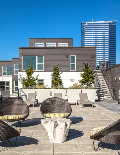 A rooftop patio with wicker furniture and a view of the city.