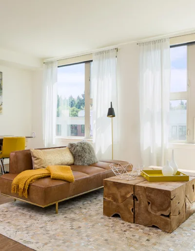 A living room with yellow furniture and a large window.
